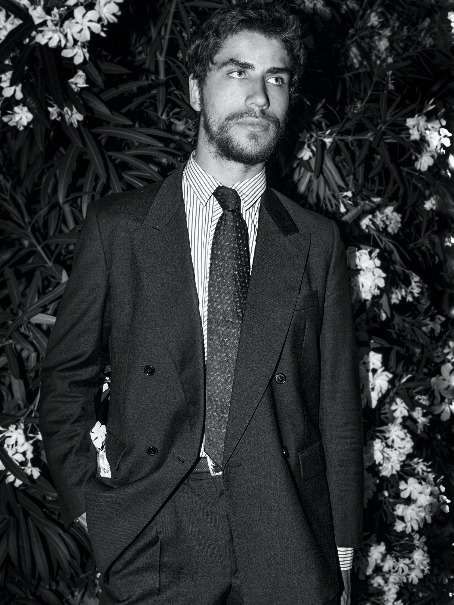 young-man-looking-away-while-standing-against-plants