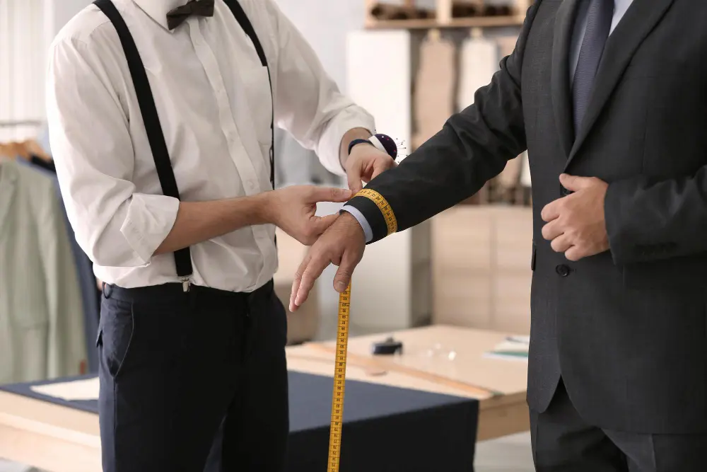 Tailor adjusting the waist of business trousers or measuring a professional client.